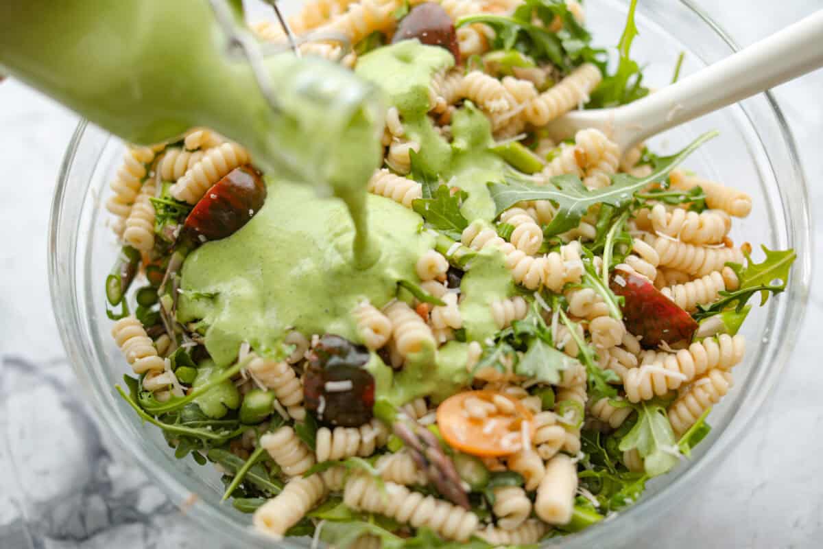 Process shot of someone pouring the dressing over the combined salad ingredients. 