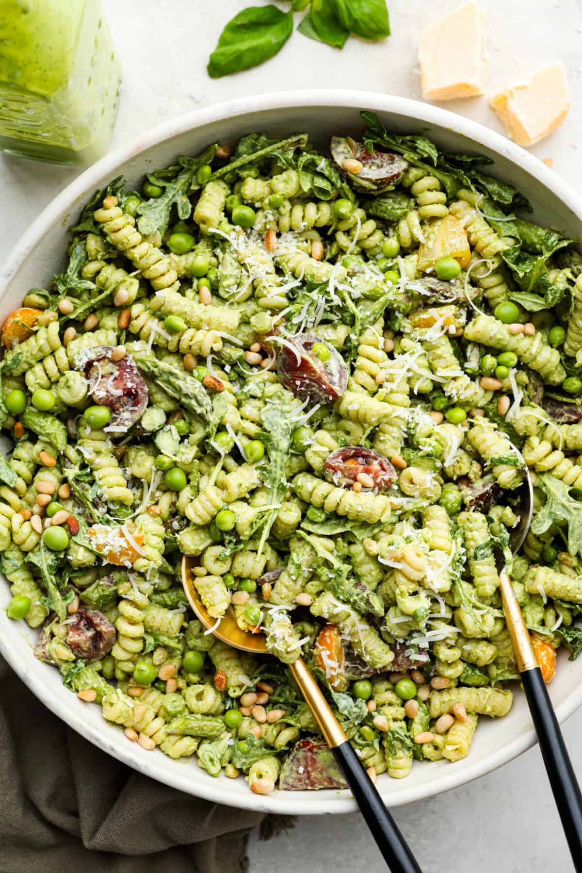 Overhead shot of green goddess pasta salad in a large serving dish with serving spoons. 