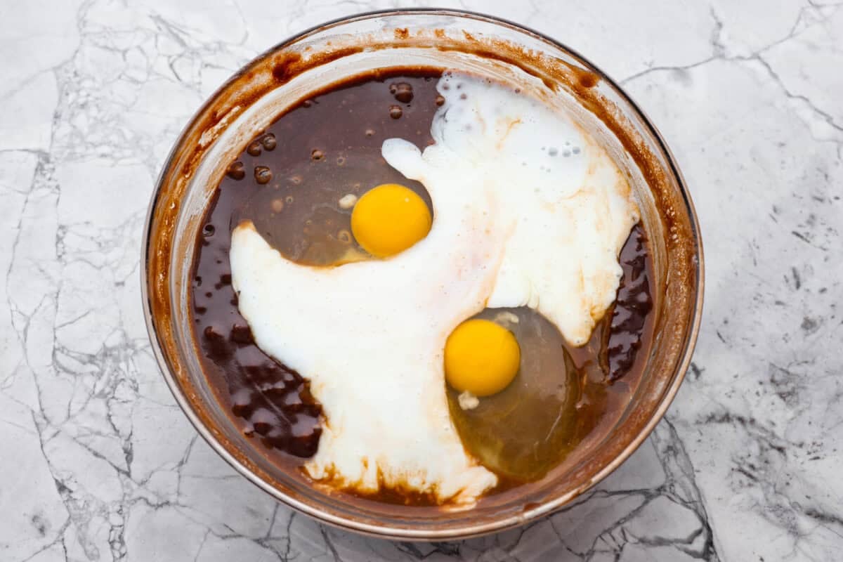 Eggs and buttermilk added to cake batter in a bowl.