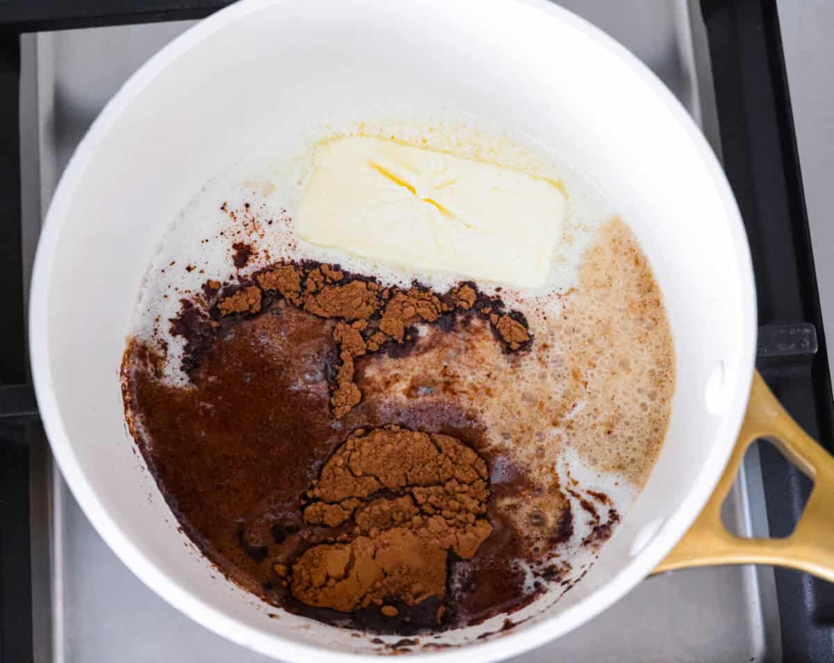 Butter, Dr. pepper, milk, and cocoa powder melting in a saucepan.