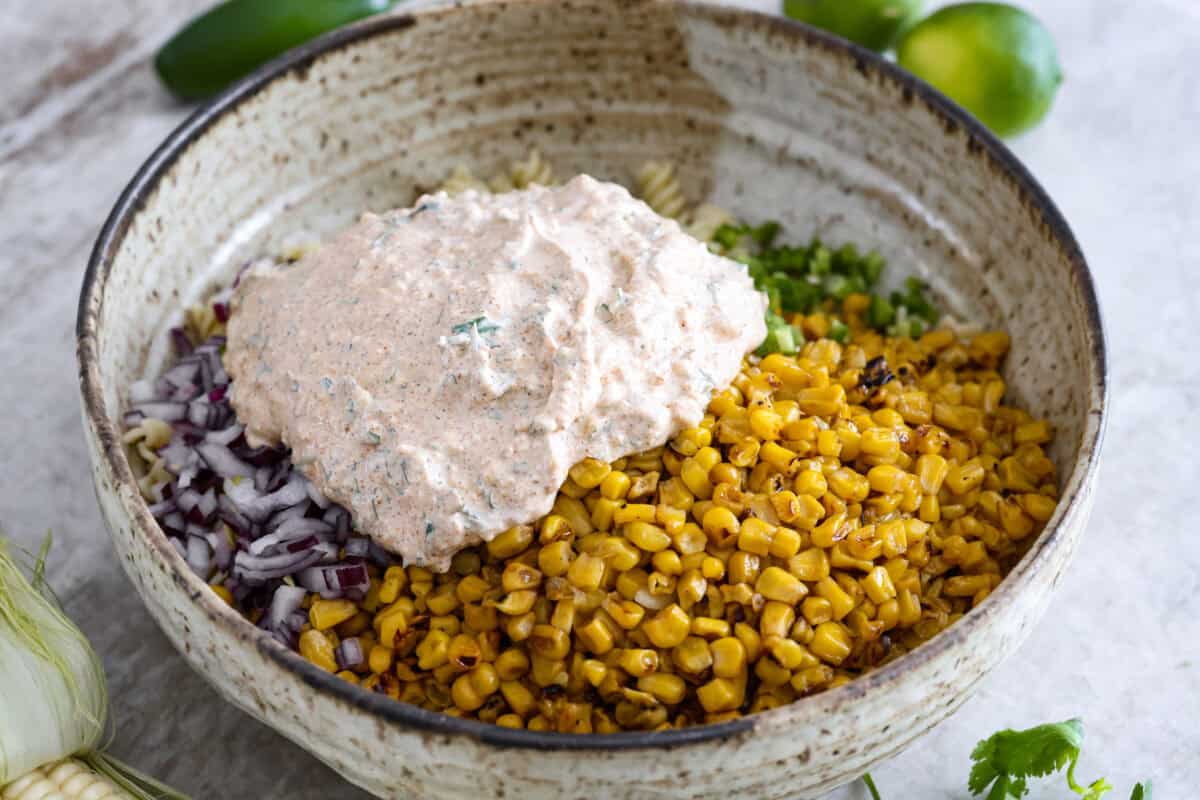 Dressing added to the bowl of pasta, corn, onion and jalapeno. 