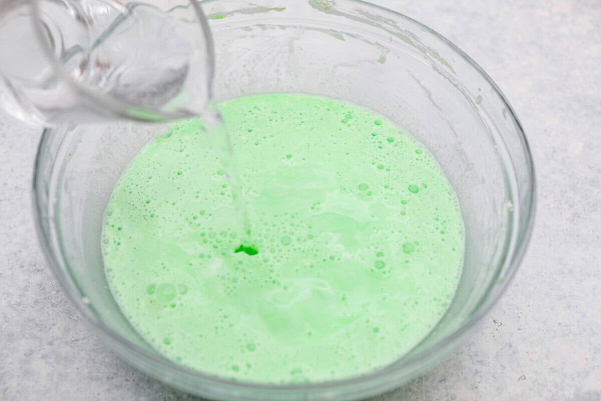 Someone pouring 7Up into the cream cheese mixture. 