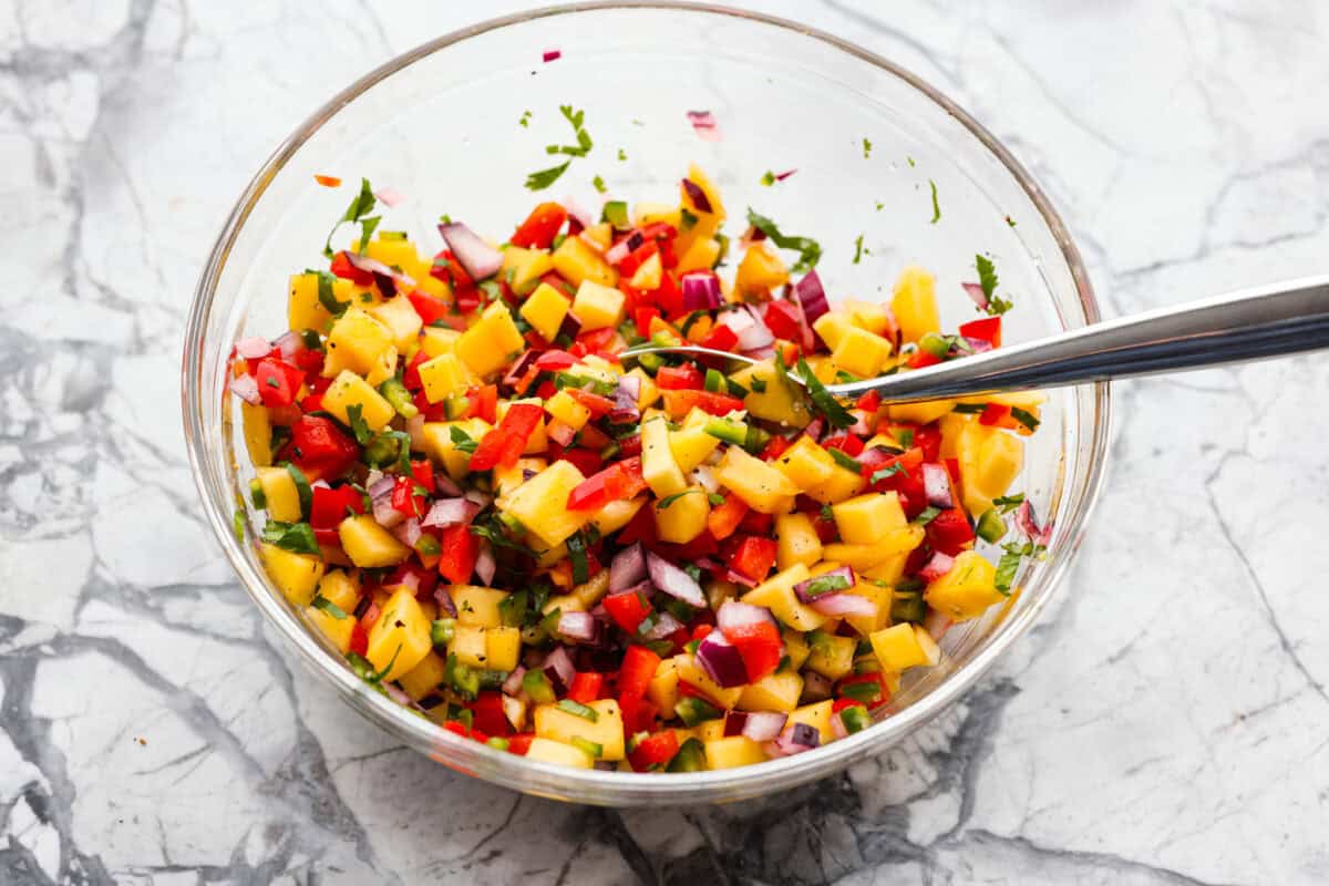 Bowl of mango salsa ingredients diced and mixed together. 