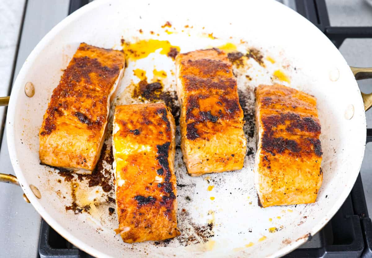 Filets cooking in a pan on a stove top. 