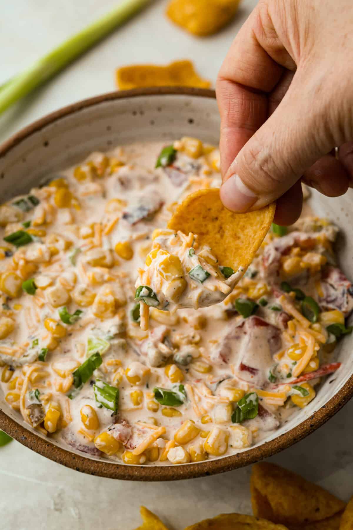 Someone scooping crack corn dip with a corn chip. 