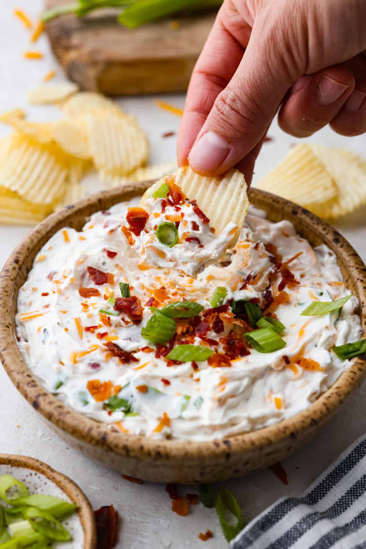 Someone taking a scoop of the completed dip with a chip. 