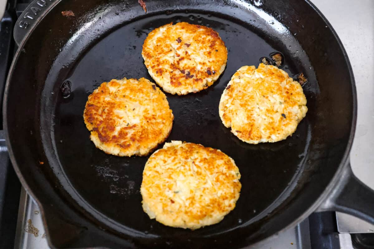 Patties frying in a skillet. 