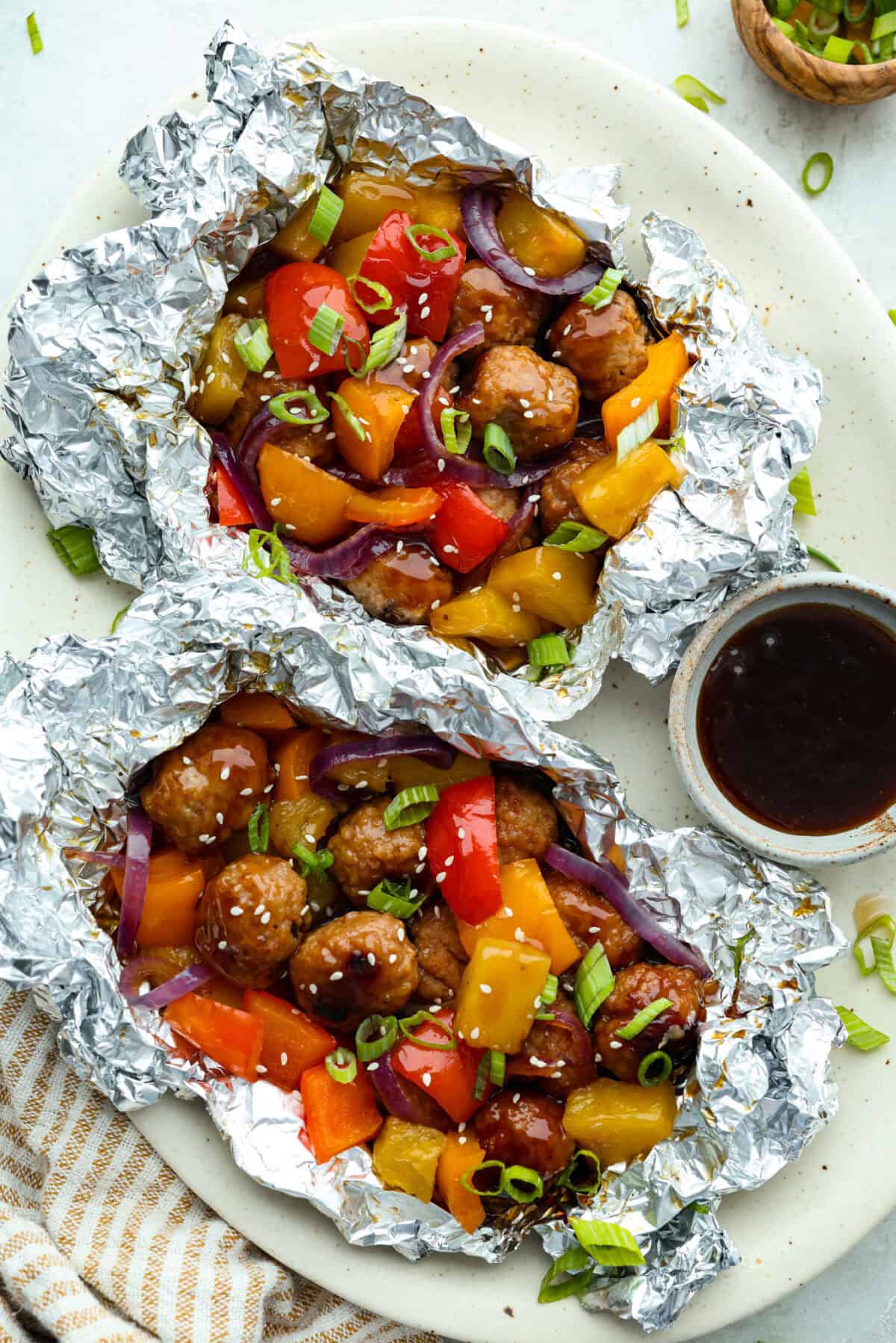 Overhead shot of plated teriyaki meatball foil packets.