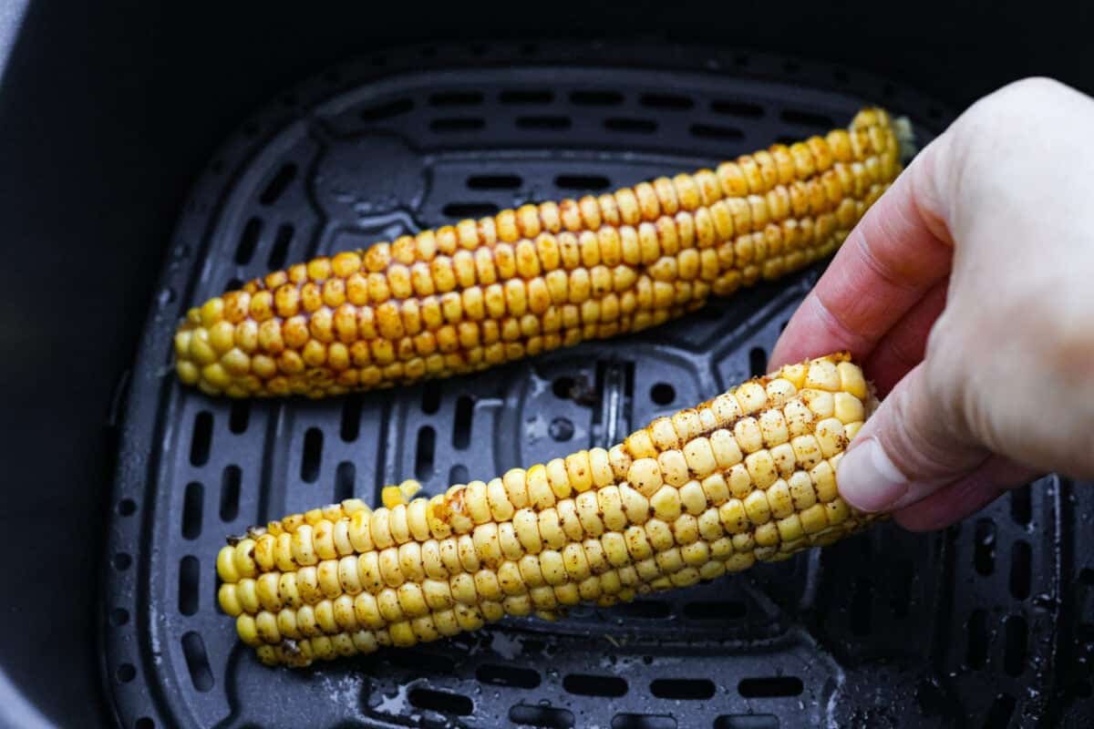 Someone placing corn ribs into the air fryer. 