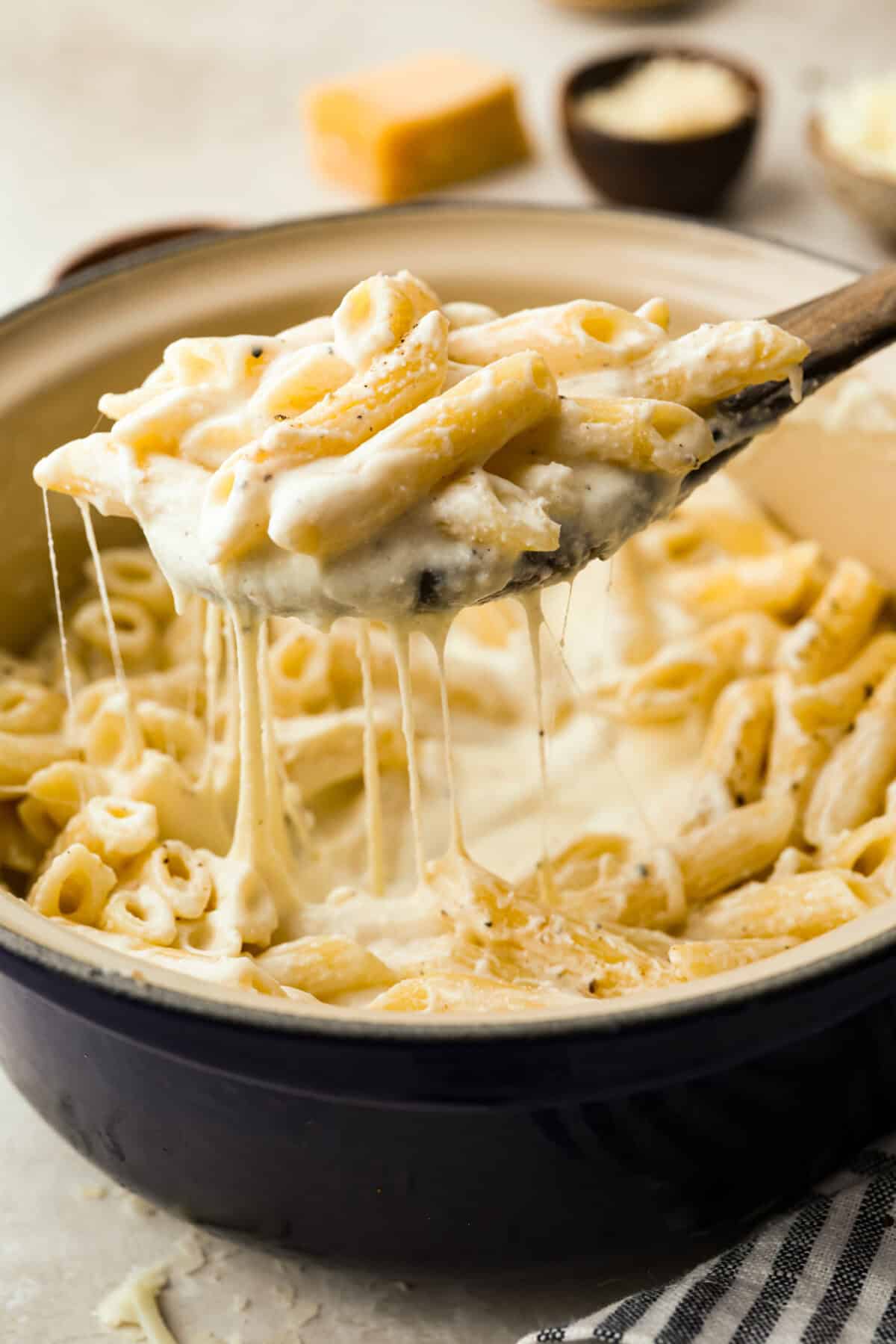 Someone lifting a scoop of four cheese pasta out of the pan.