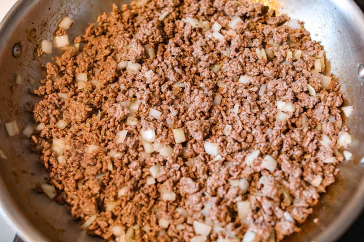 Ground beef and onions being cooked in a skillet. 