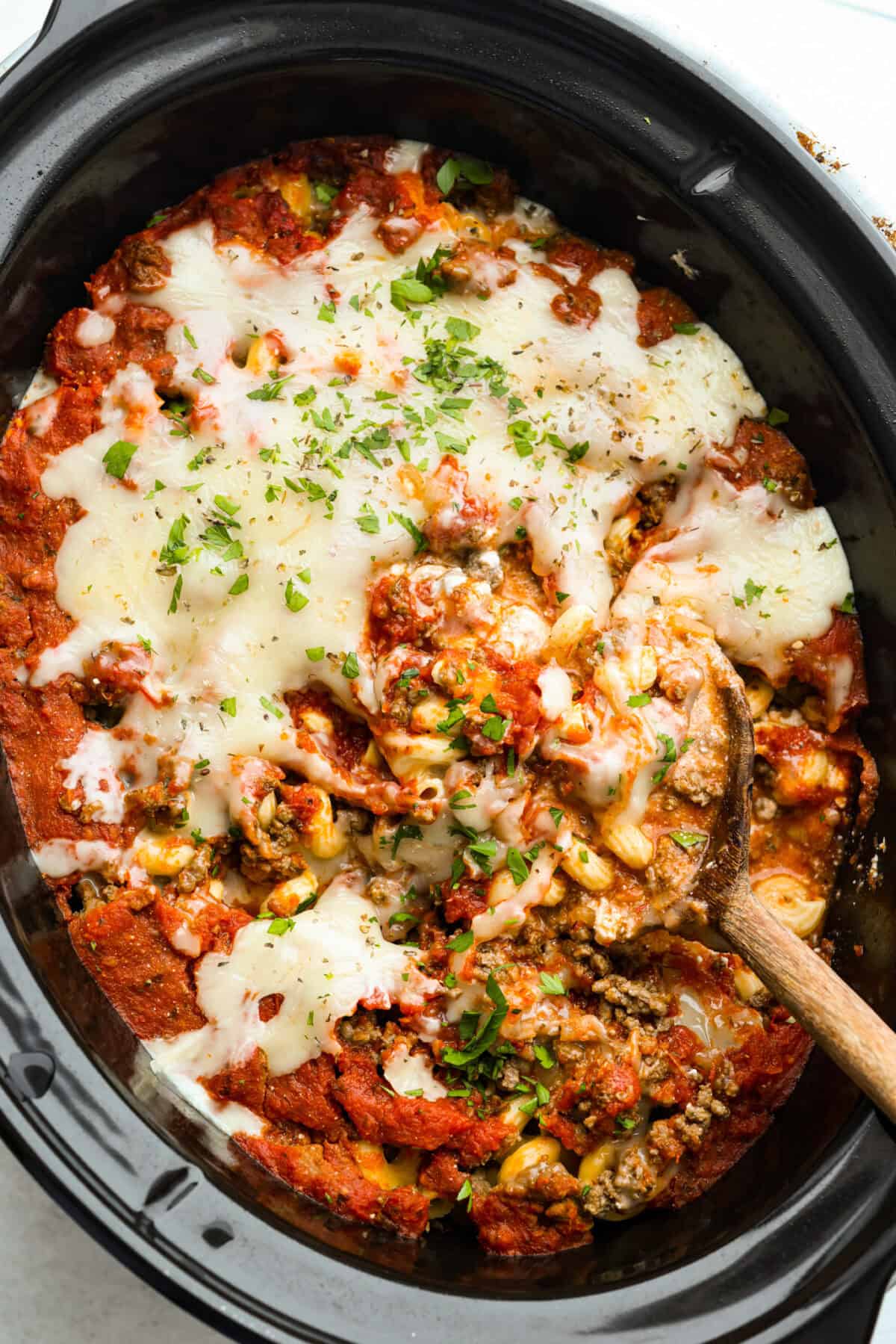 Overhead shot of crockpot million dollar pasta with a wooden spoon. 