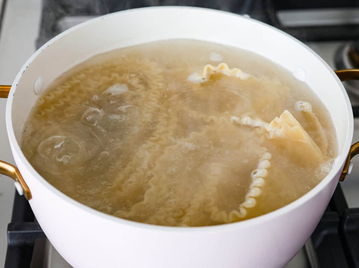 Lasagna noodles in boiling water in a pot. 