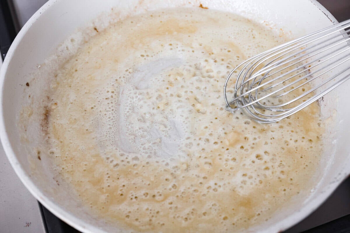 Melted butter, garlic and flour being whisked together to create a roux. 