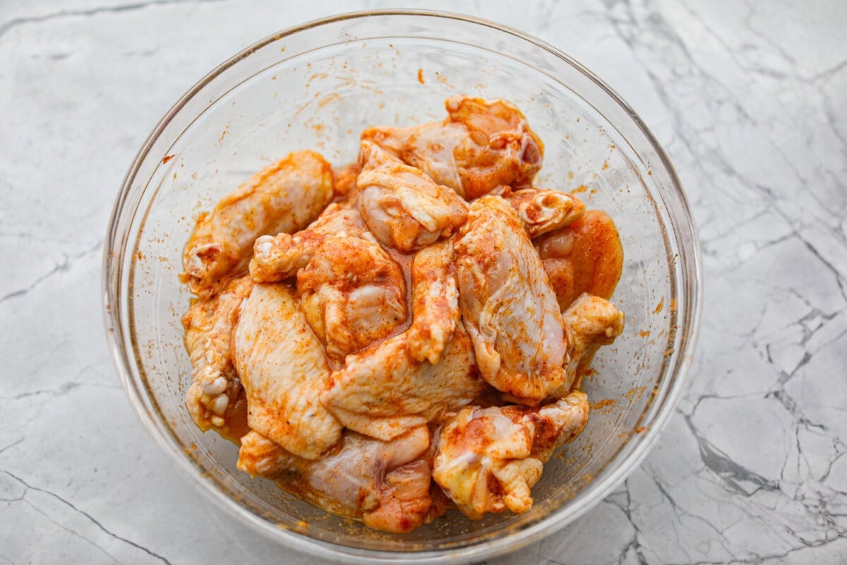 Chicken wings smothered in seasoning rub sitting in a bowl. 