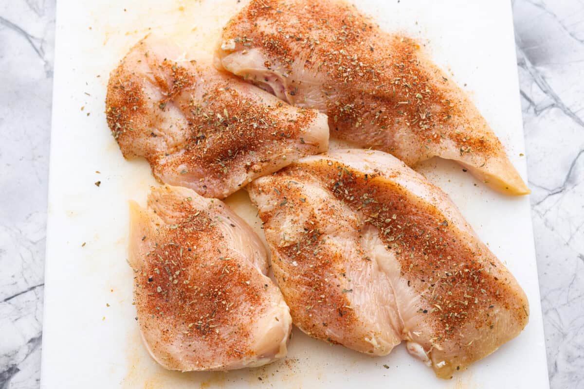 Overhead shot of seasoned chicken on a cutting board. 