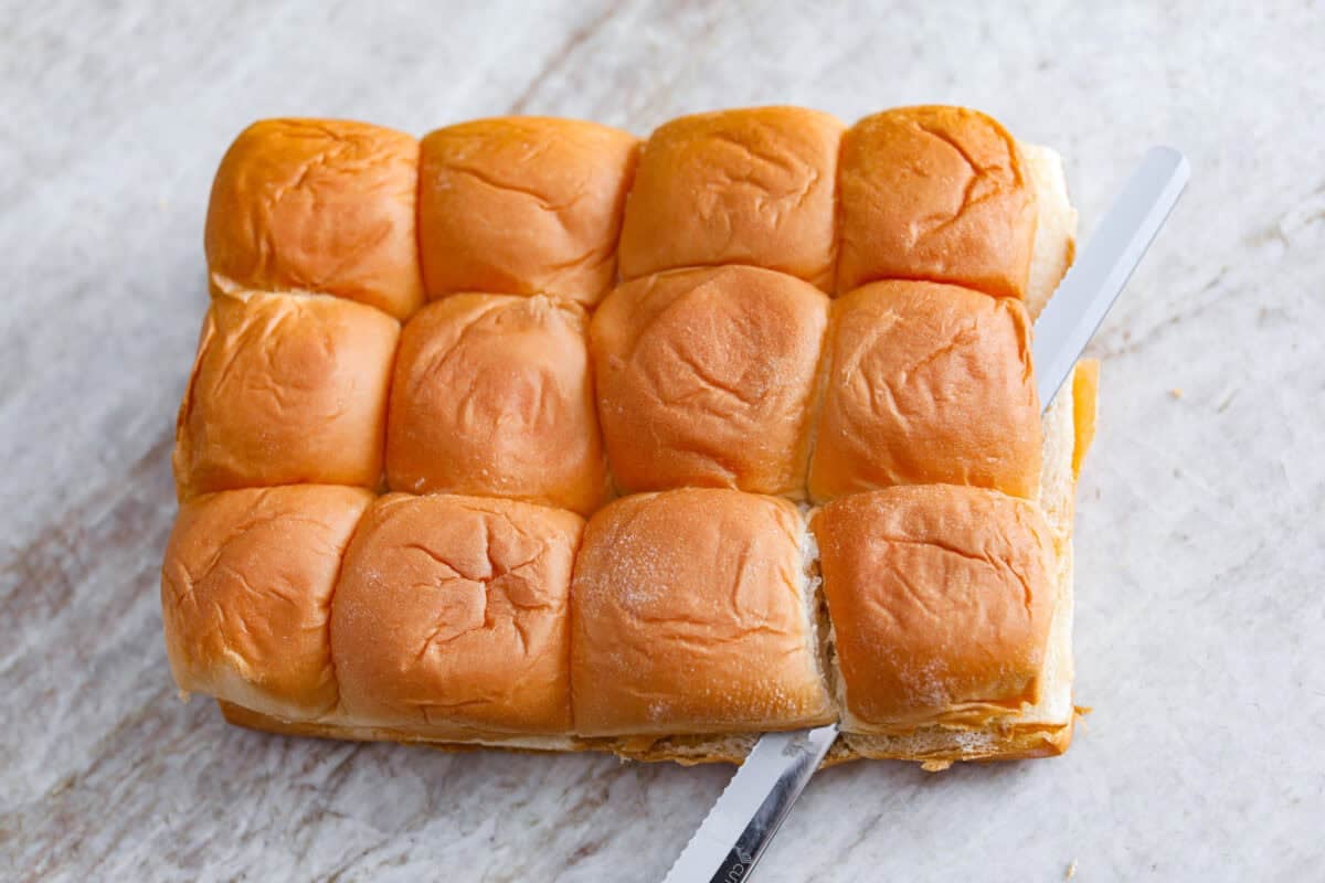 The top half of the Hawaiian rolls being cut off. 
