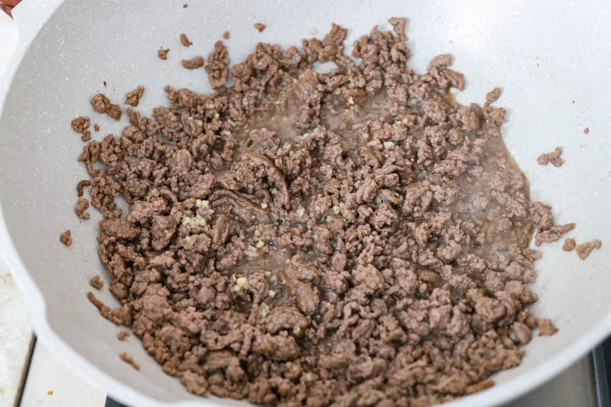 Ground beef and garlic cooking in a skillet. 