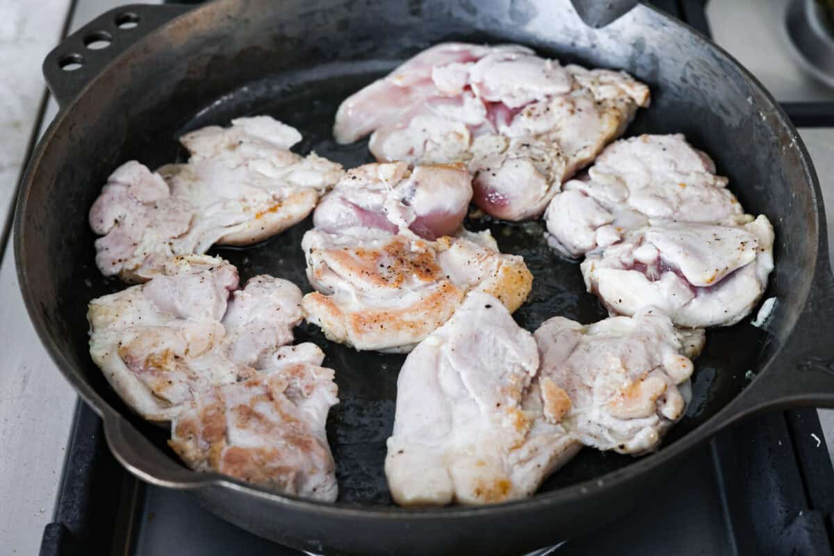 Chicken thighs cooking in a skillet. 