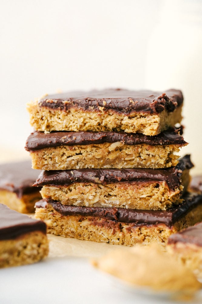 These peanut butter bars are thick, rich, and heavenly! A thick layer of peanut butter mixed with rolled oats makes a creamy filling with a smooth chocolatey frosting that is an irresistible combination. A stack of peanut butter bars.