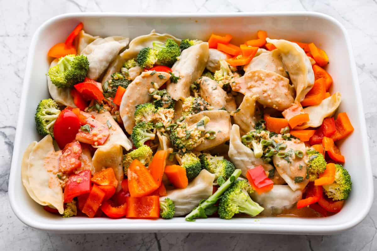 Sauce poured on top of the potstickers and veggies all read yto be baked. 