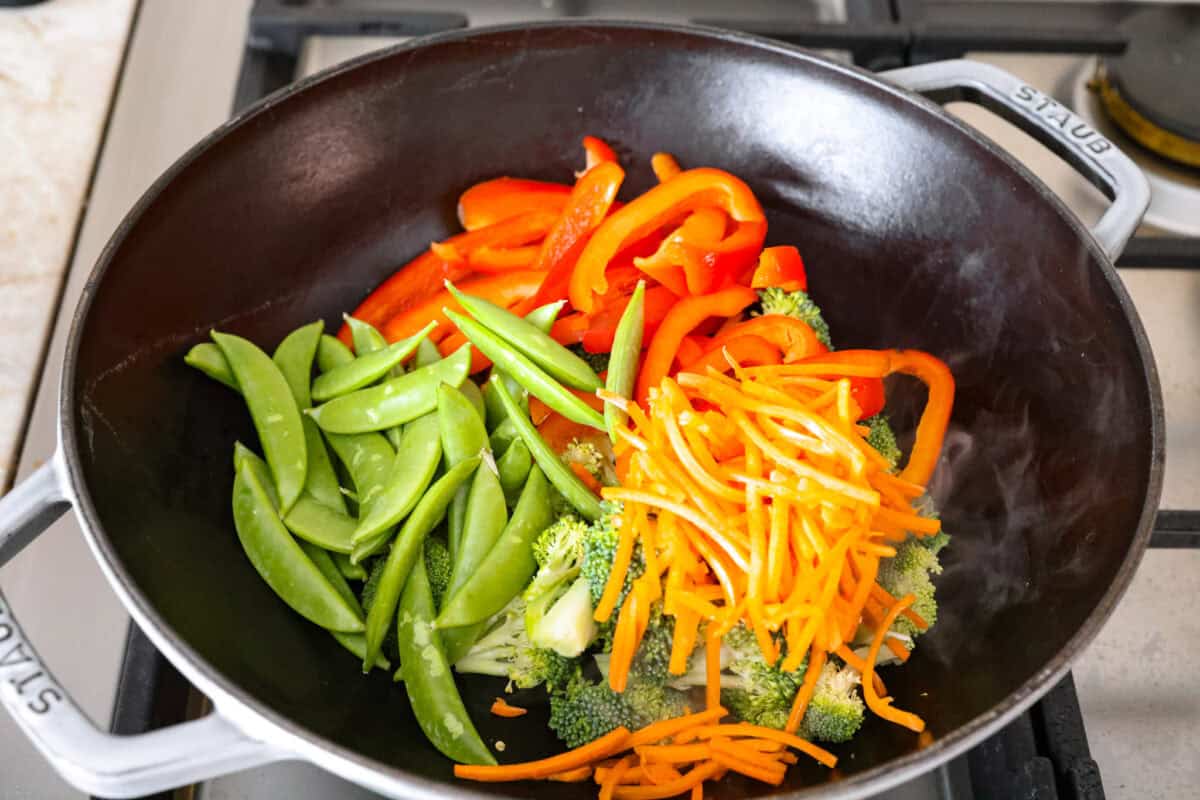 Veggies cut up and tossed in vegetable oil in a wok.