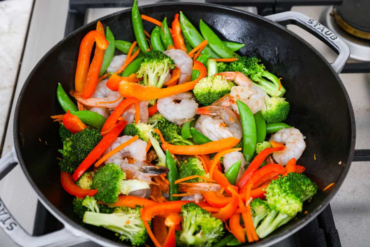 Shrimp added to the veggies in the wok. 