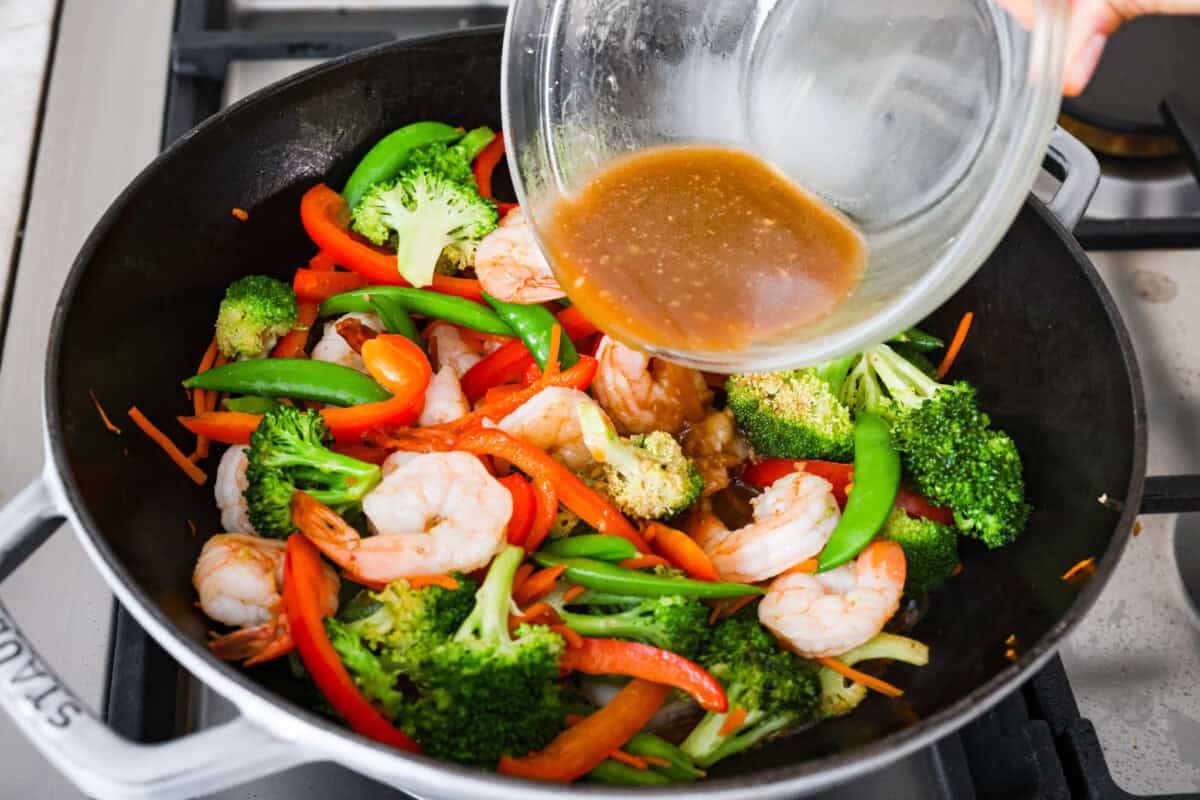 Garlic sauce poured over shrimp and veggies in the wok. 