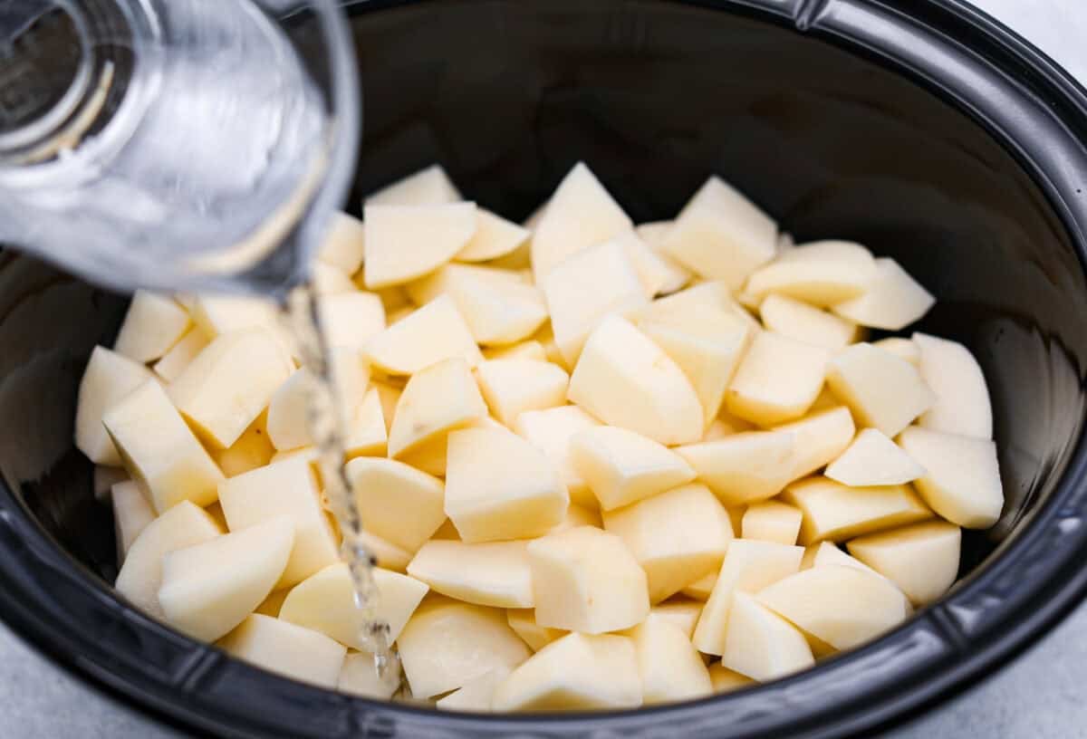 Someone pouring water in the crockpot.