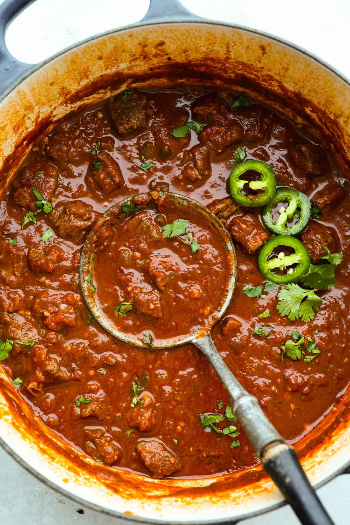 Do you like your chili with beans or without? This authentic Texas chili keeps it classic. Just bold, tender chuck roast, without beans. It has a rich, smoky flavor in every bite. Overhead shot of Texas chili with some fresh cilantro and jalapeños.