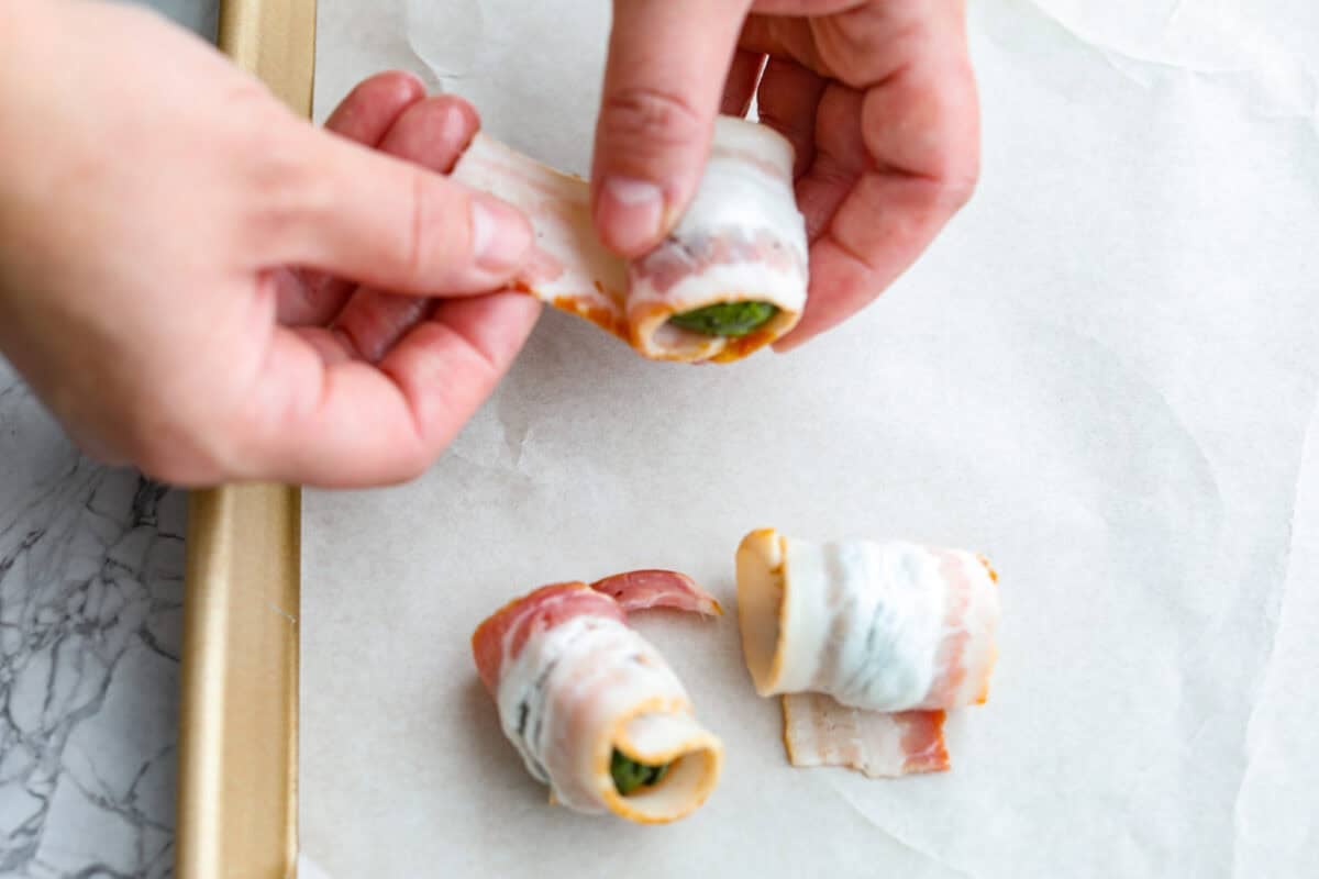 Someone wrapping the Brussels sprouts with bacon. 