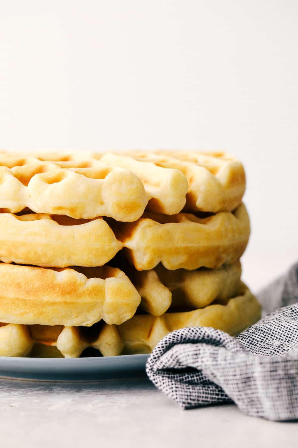 There’s nothing like my homemade Belgian waffles! They're crisp on the outside, soft and fluffy inside, with deep pockets for all the syrup and butter. The secret is whipping the egg whites for that light, airy texture! Stack of Belgian waffles on a plate.