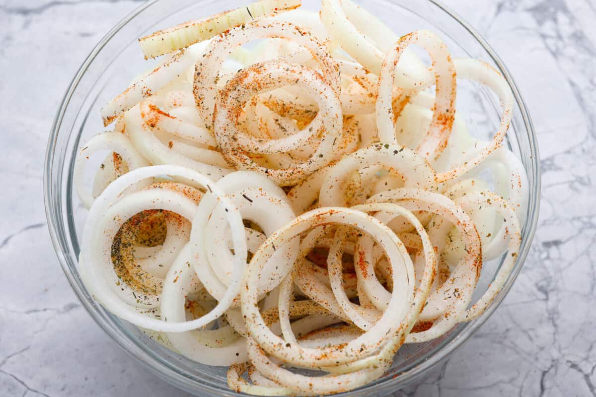 Sliced onions seasoned in a bowl. 