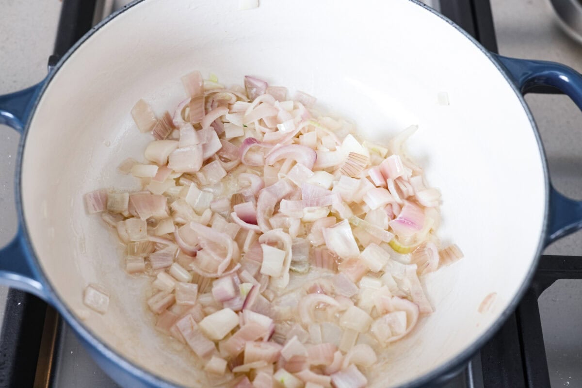 Creamy roasted garlic soup is comfort food with a side of obsession. Combining roasted garlic, tender potatoes, and nutty Parmesan into a cozy soup is absolute perfection. Just make sure you serve it to anyone within hugging distance. Shallots cooking in butter in a skillet.