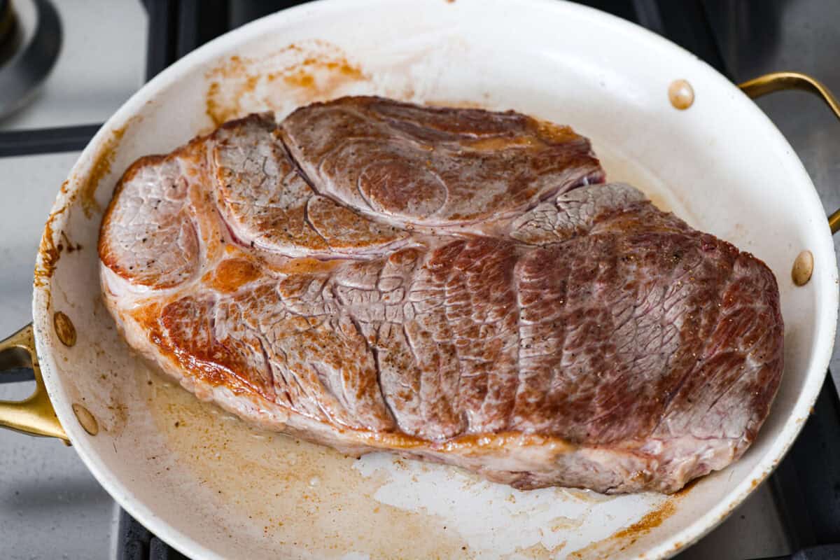 Roast searing in a pan on the stove. 