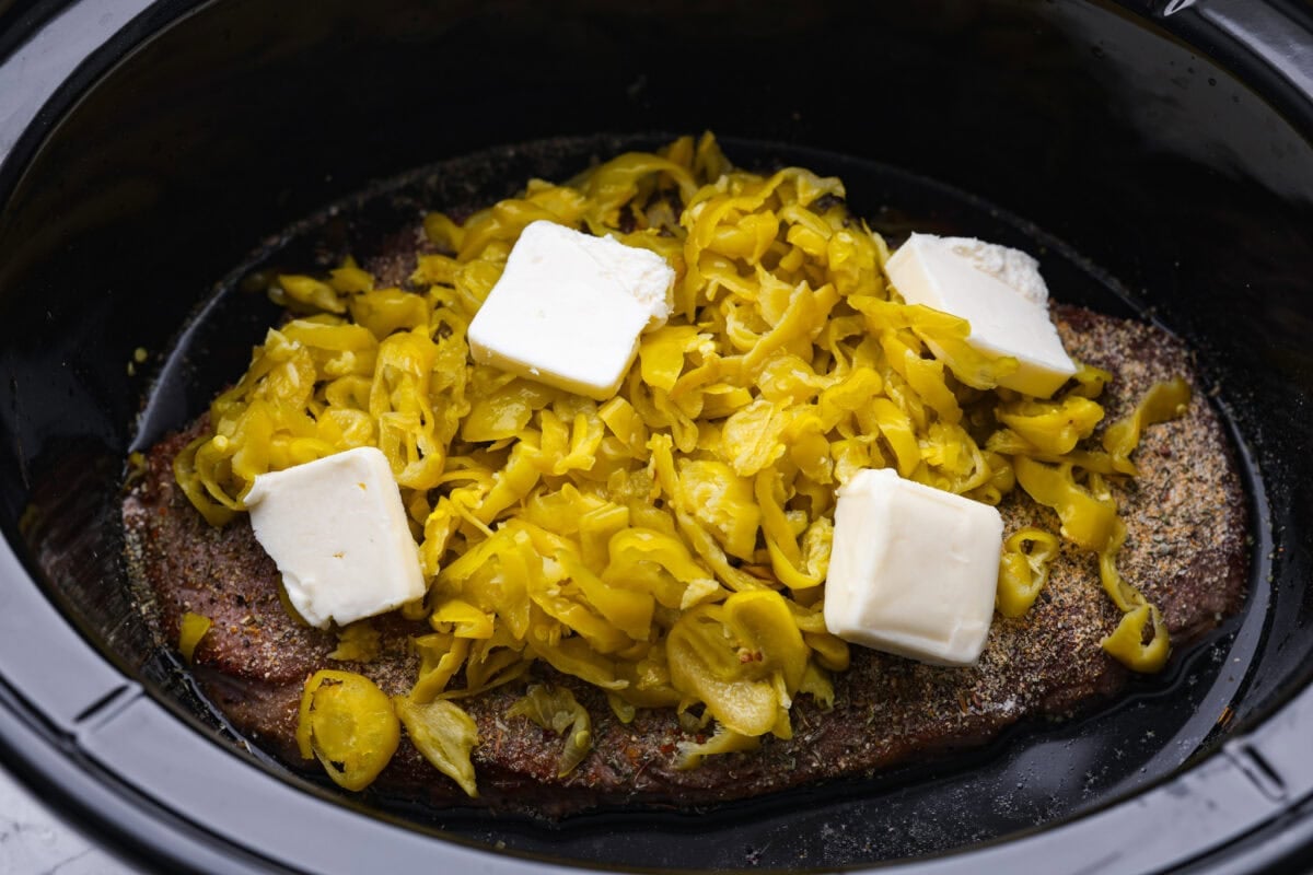 Ingredients added to the top of the beef in the crockpot.