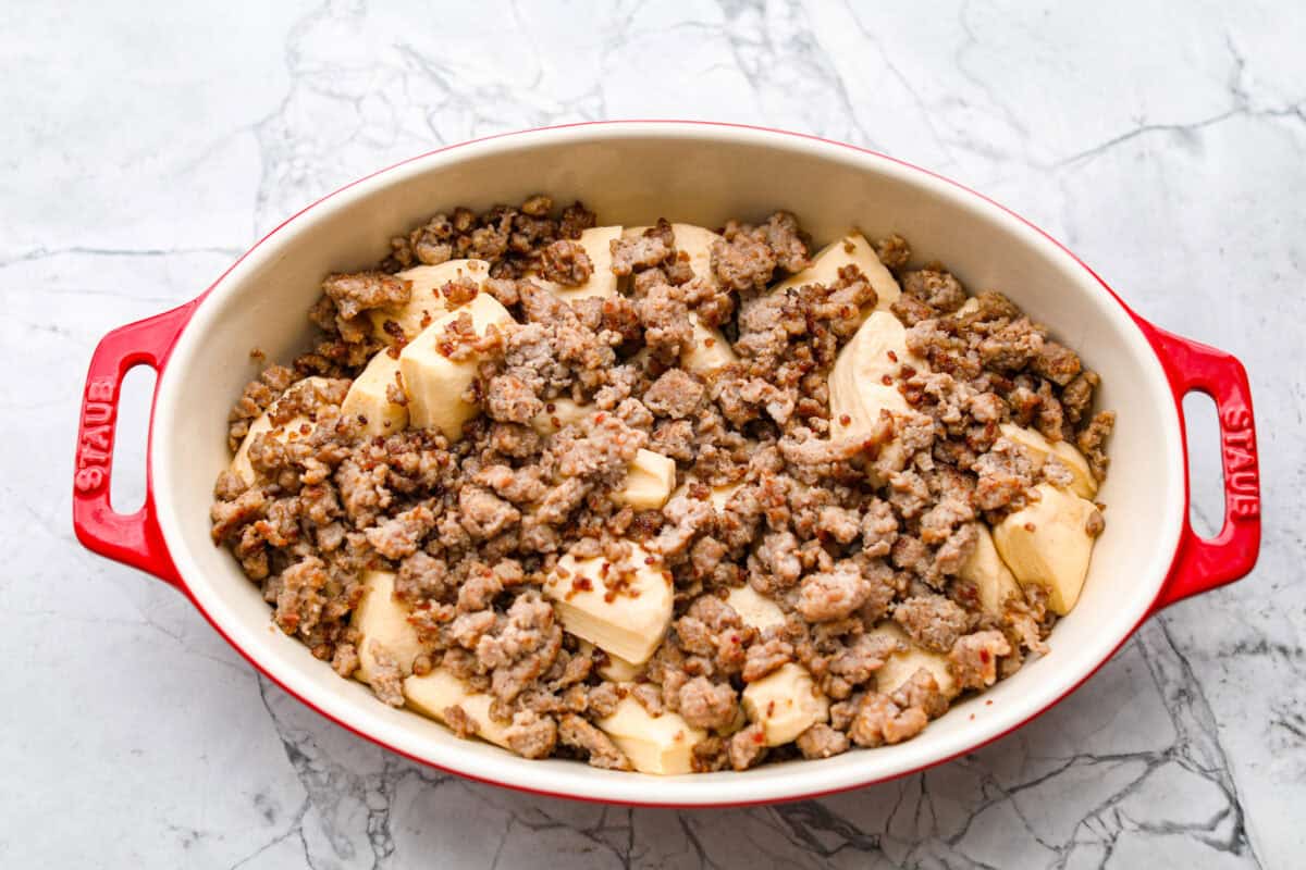 Cooked sausage and cut up biscuits together in a baking dish.