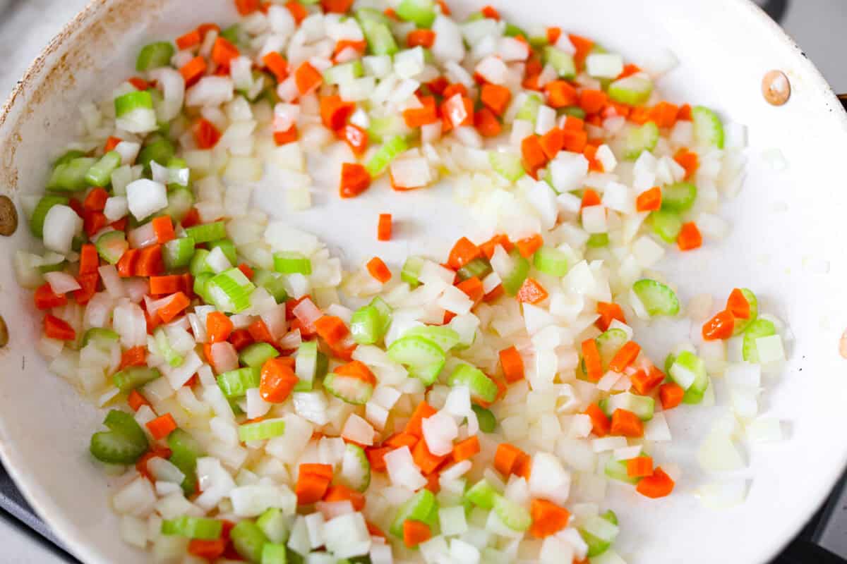 Carrots, onion, and celery cooking in a skillet.