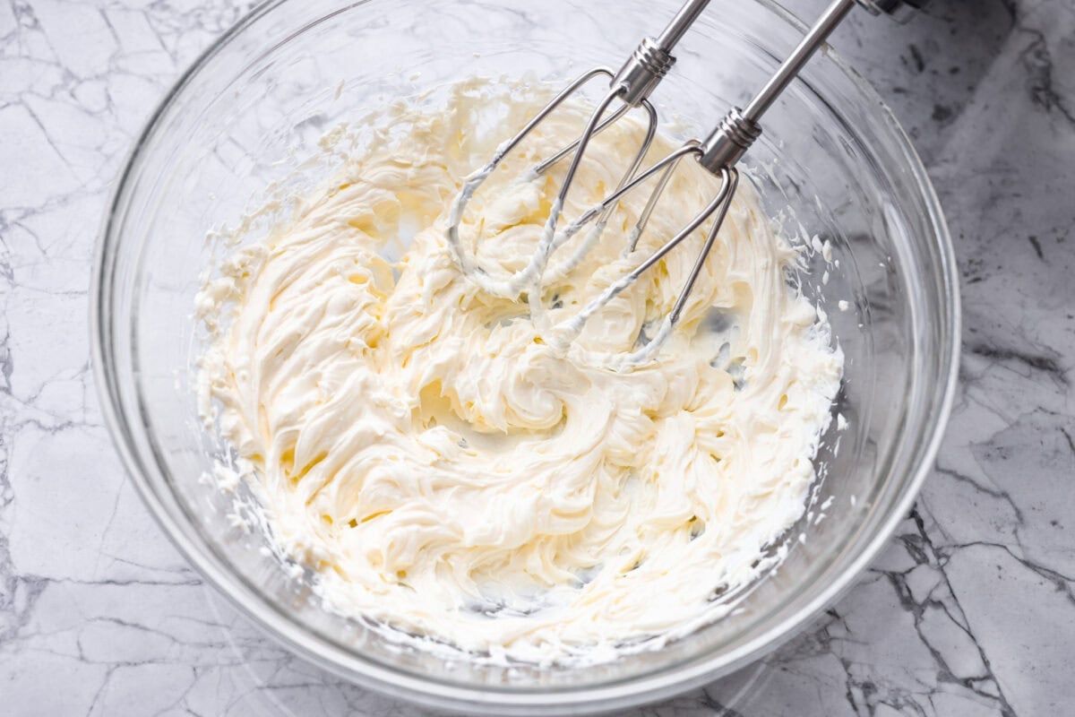 This Mississippi sin dip is pure comfort-food goodness. Creamy, cheesy, a little smoky, and baked into a loaf of French bread, it’s the kind of snack everyone gathers around and keeps going back for! Someone using a had mixer to beat the cream cheese.