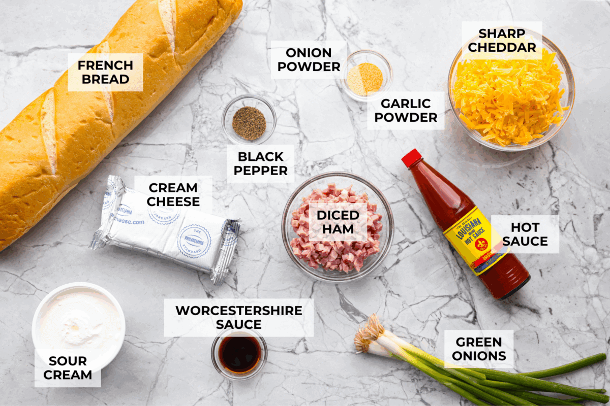 This Mississippi sin dip is pure comfort-food goodness. Creamy, cheesy, a little smoky, and baked into a loaf of French bread, it’s the kind of snack everyone gathers around and keeps going back for! Overhead shot of labeled Mississippi sin dip ingredients.
