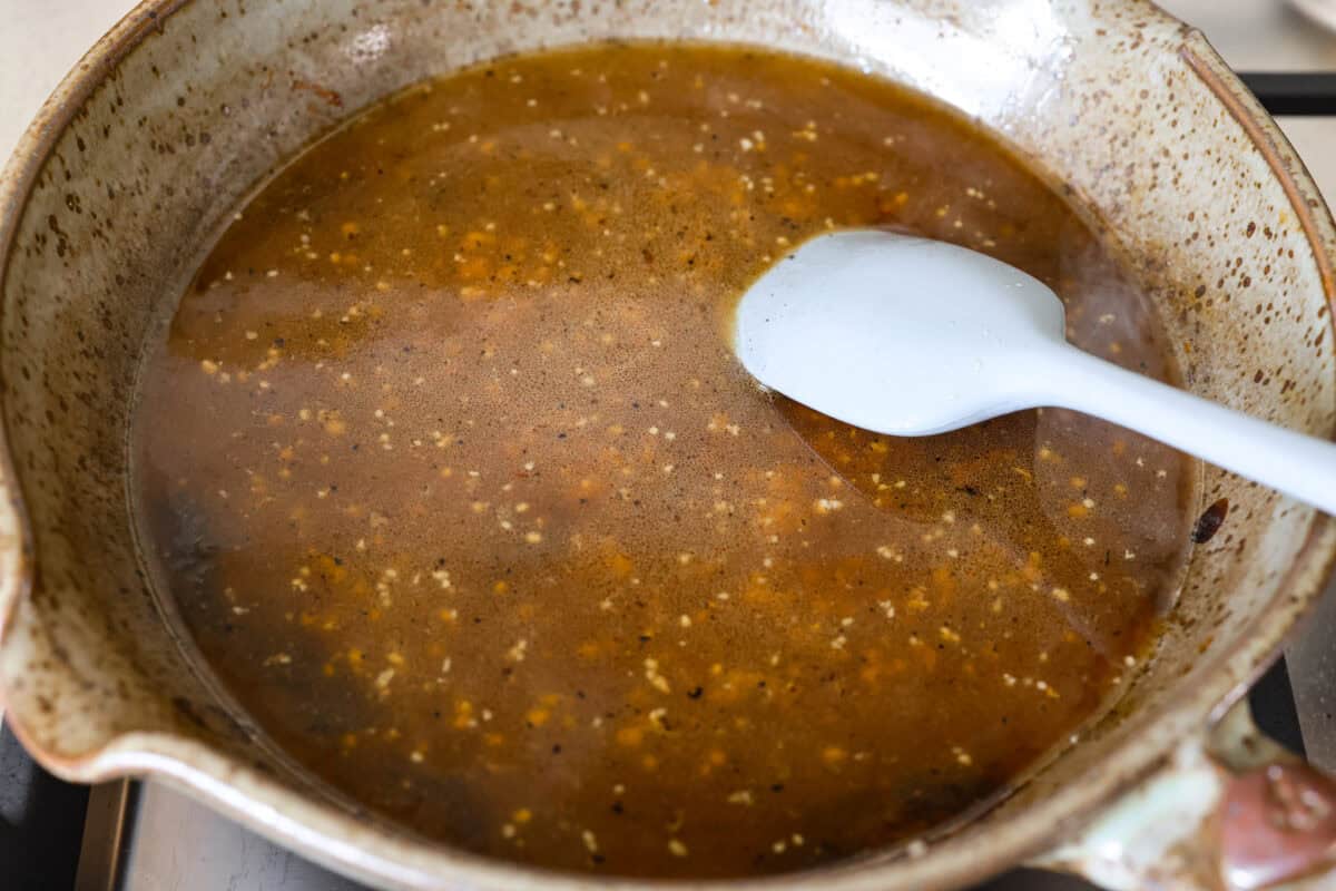 Melted butter, minced garlic, and chicken broth added to the skillet.