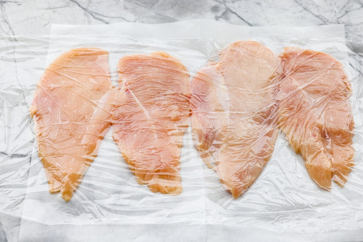 Chicken breasts cut in half and placed between plastic wrap and smashed with a meat mallet.