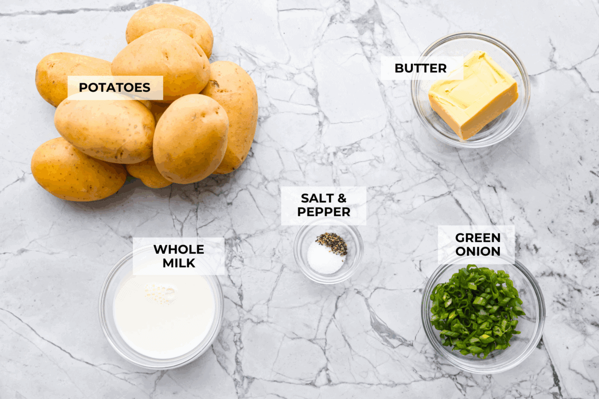 Irish champ potatoes are mashed potatoes done right. Fluffy spuds meet warm onion kissed milk and a generous melt of Irish butter for a side that’s simple, rustic, and seriously so good! Overhead shot of labeled Irish champ potatoes ingredients.