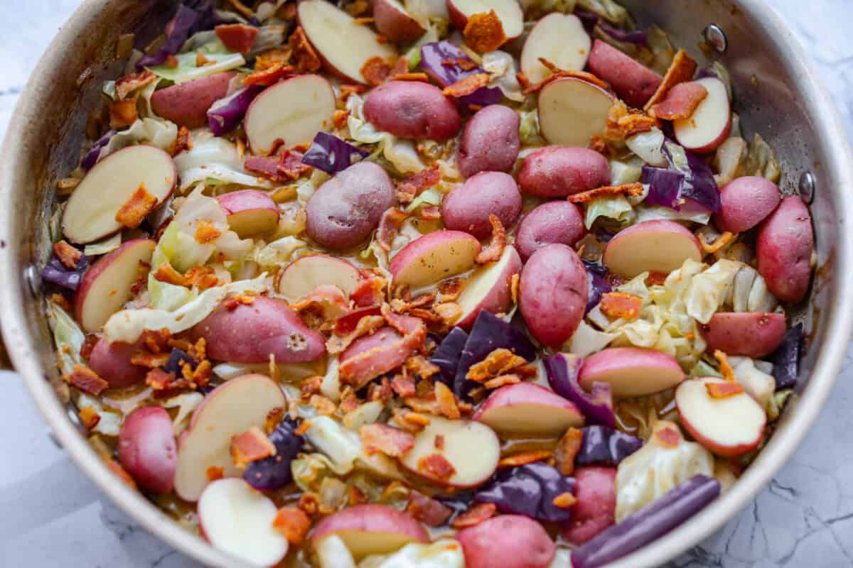 This Irish chicken is my cozy mashup of pub vibes and weeknight reality. Seared chicken thighs baked over bacon, cabbage, and potatoes, then I add a splash of Irish whiskey and a touch of cream to make the whole pan taste extra special. Potatoes and bacon added to the skillet.