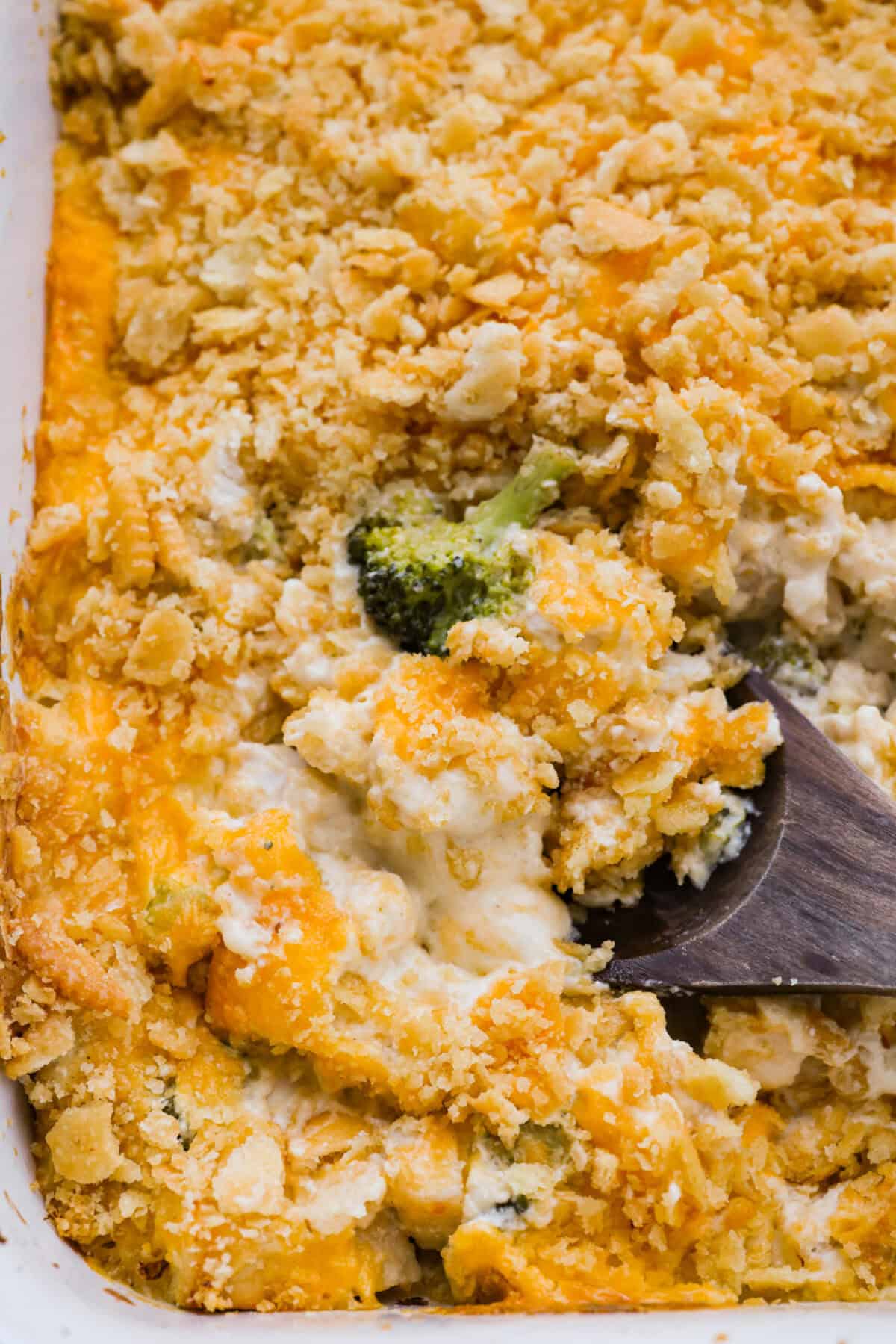 Fully baked chicken divan casserole with a serving spoon taking a scoop.