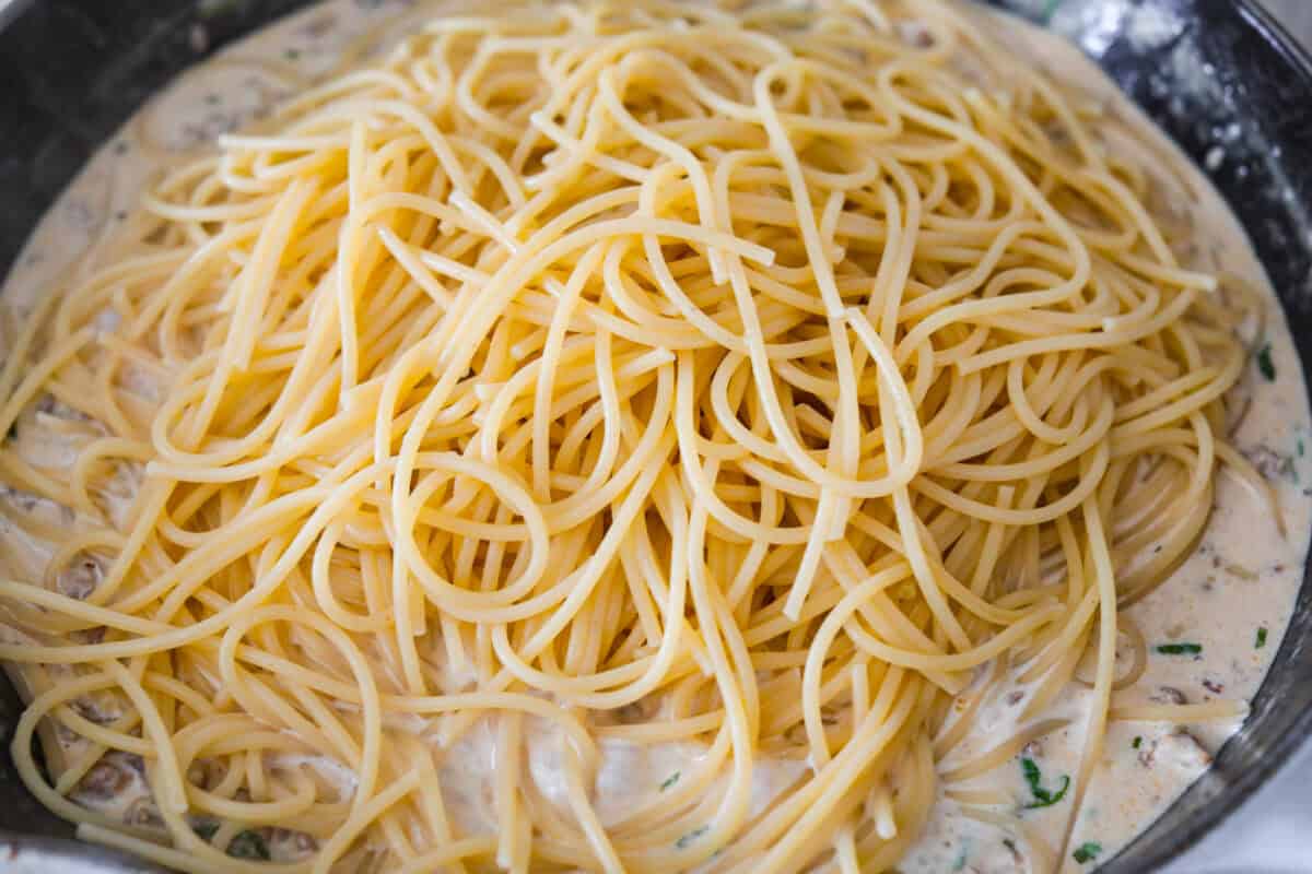 If you love a creamy pasta with big flavor, this creamy sausage spaghetti needs to be on your menu. Smoked Gouda adds depth, the sausage brings a little heat, and fresh basil adds brightness. Simple ingredients, quick to make, and always a hit! Cooked spaghetti added to the skillet.