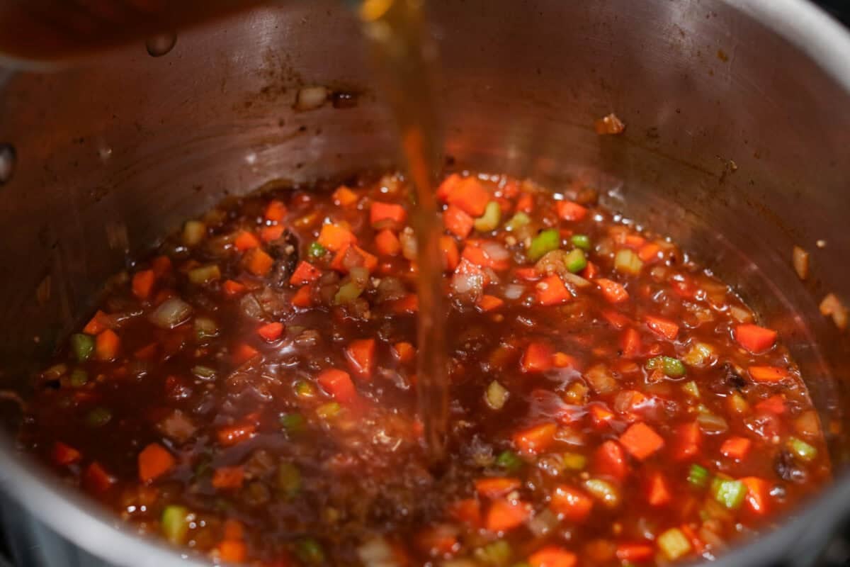 Meet Stracotto, the Italian pot roast you didn't know you were missing! A seared roast is slowly braised in a rich, hearty tomato sauce until it is melt-in-your-mouth tender. The sauce alone is worth making this recipe for! Beef broth being added to the veggie and wine mixture.