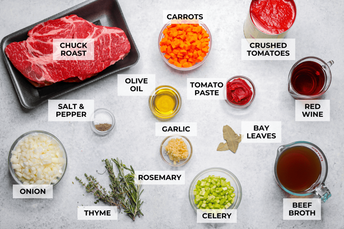 Meet Stracotto, the Italian pot roast you didn't know you were missing! A seared roast is slowly braised in a rich, hearty tomato sauce until it is melt-in-your-mouth tender. The sauce alone is worth making this recipe for! Overhead shot of labeled Italian pot roast ingredients.
