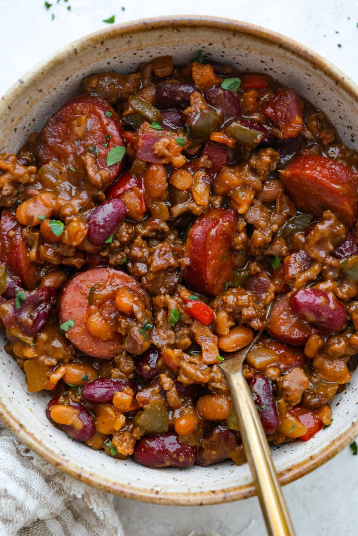 Bowl of loaded baked beans with a gold spoon.