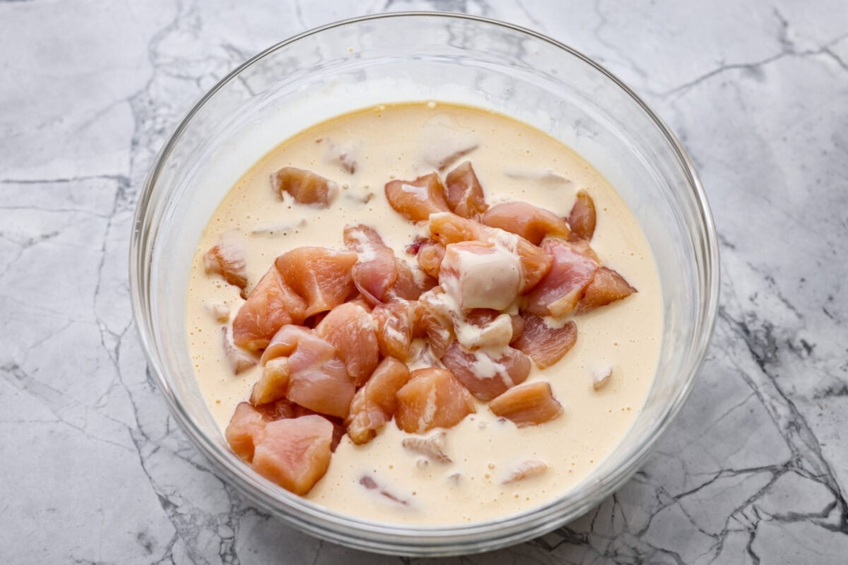 Seasoned chicken in a bowl of batter.